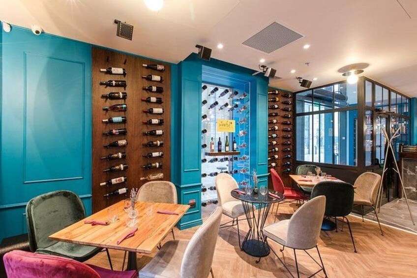 L’intérieur d’un restaurant avec des murs de couleur turquoise, des étagères à vin en bois et des sièges modernes. 3