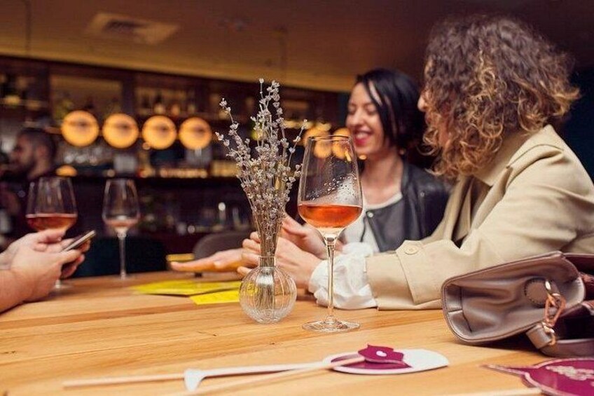 A bar setting with a vase of flowers, wine glasses, and a handbag on the table. 2