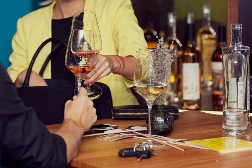 A person holding a wine glass, a bottle of wine, and a bottle of water on a table. 4