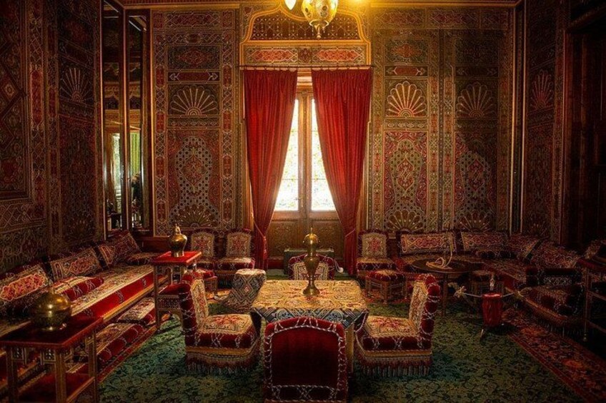 A richly decorated room with intricate patterns, a large window with red curtains, and a chandelier. 4