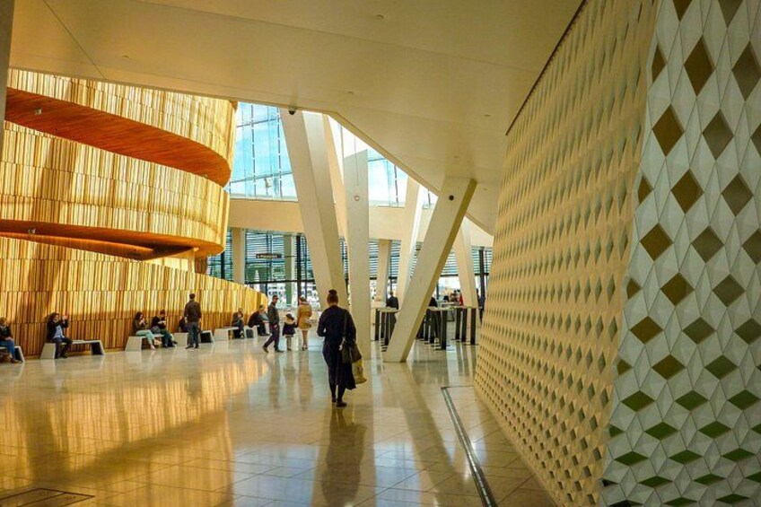 A spacious indoor area with a curved wooden structure, a patterned wall, and a high ceiling. 1