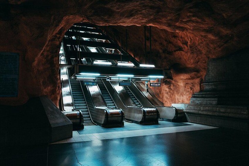 An underground metro station with escalators and a tiled floor. 4