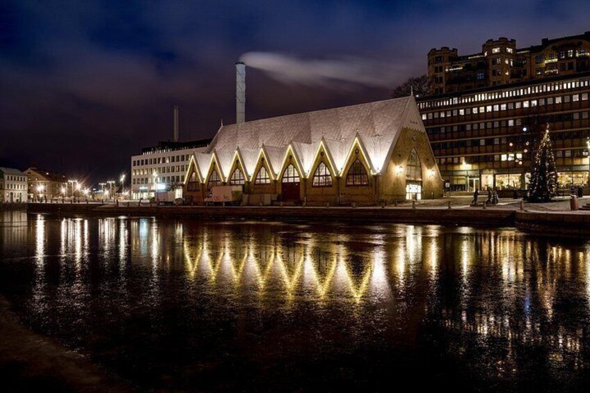 Een gebouw aan het water met een opvallend driehoeks dak en meerdere ramen, dat in het water wordt weerkaatst. 2