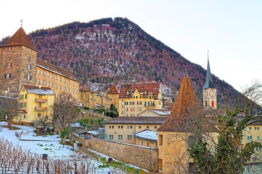 A town with historic buildings, a church, and a mountain backdrop. 4