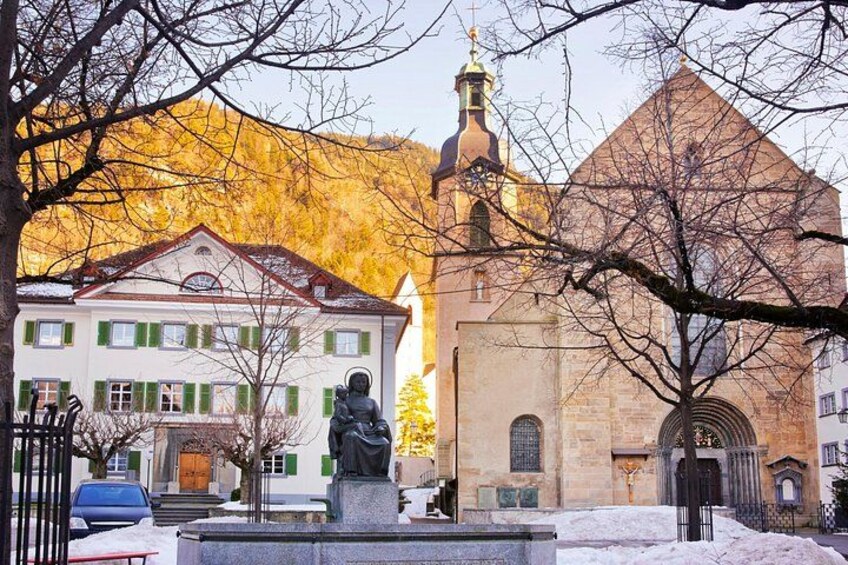 A statue in front of a church with a snow-covered ground. 5