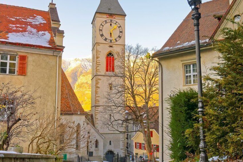 A church with a clock tower, snow on the roof, and autumn trees. 2
