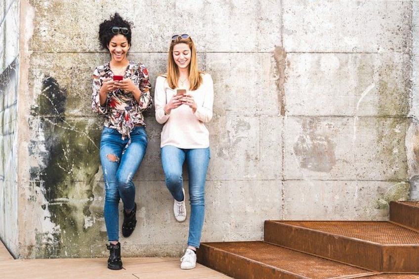Two individuals sitting on steps against a textured wall. 3