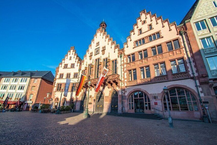 A historic building with ornate architecture, cobblestone street, and flags. 2
