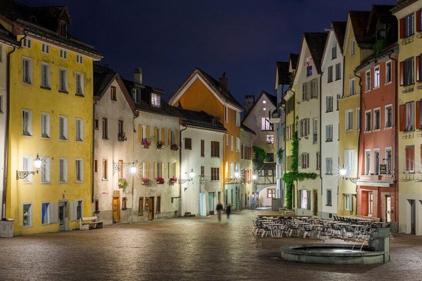 A cobblestone street lined with colorful buildings at twilight. 4
