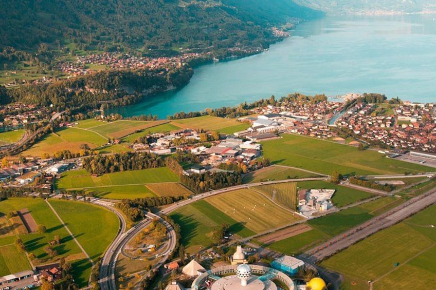 An aerial view of a town by a river, with fields, roads, and a prominent building with a dome. 3