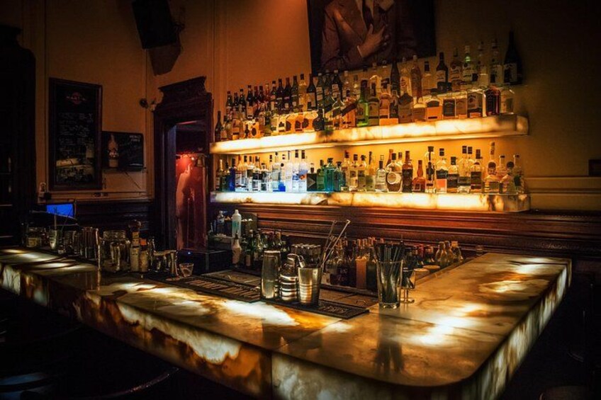 Eine Bar mit einer Holztresen, Flaschenregalen und Gläsern. 1