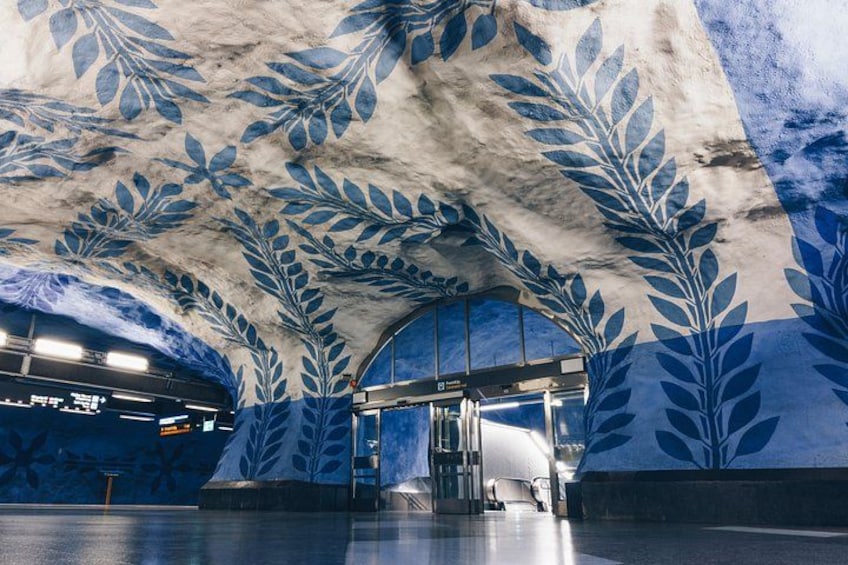 An underground station with blue leaf patterns on the walls and ceiling. 2