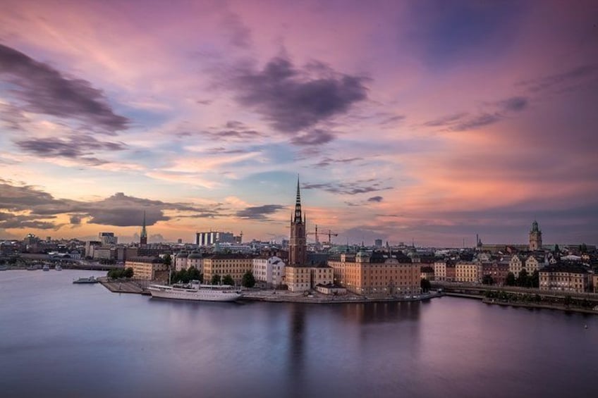A cityscape with a prominent tower, a river, and a sunset sky. 1