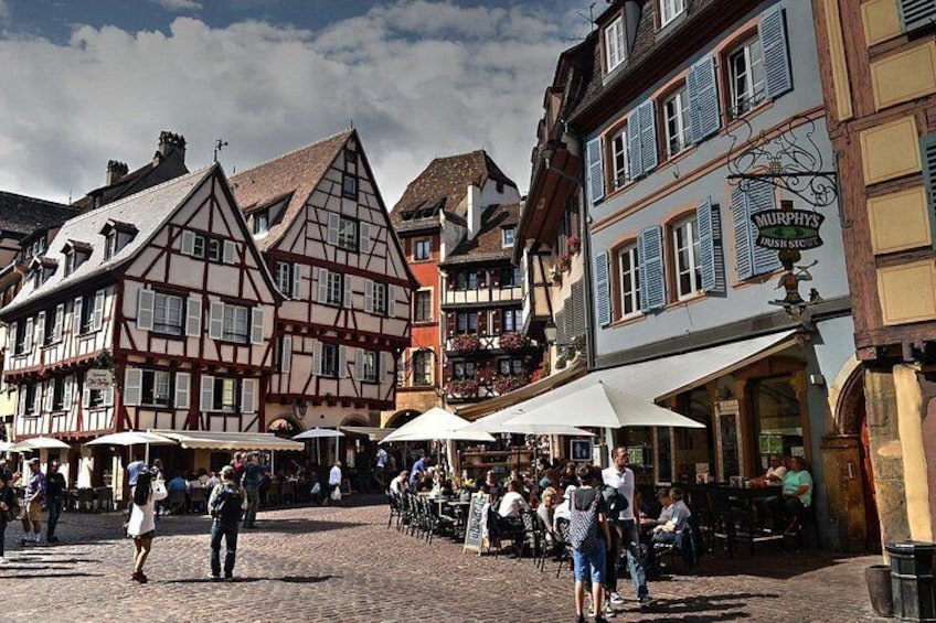 A cobblestone square with traditional half-timbered buildings, outdoor seating, and a Murphy's Irish pub. 5