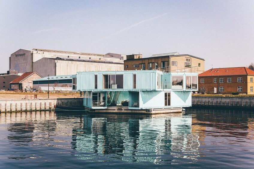 A floating houseboat on water with industrial buildings in the background. 2