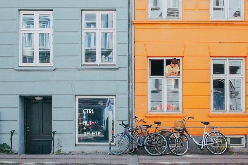 A row of bicycles parked in front of a building with a sign that reads 'CTRL DELETE'. 5