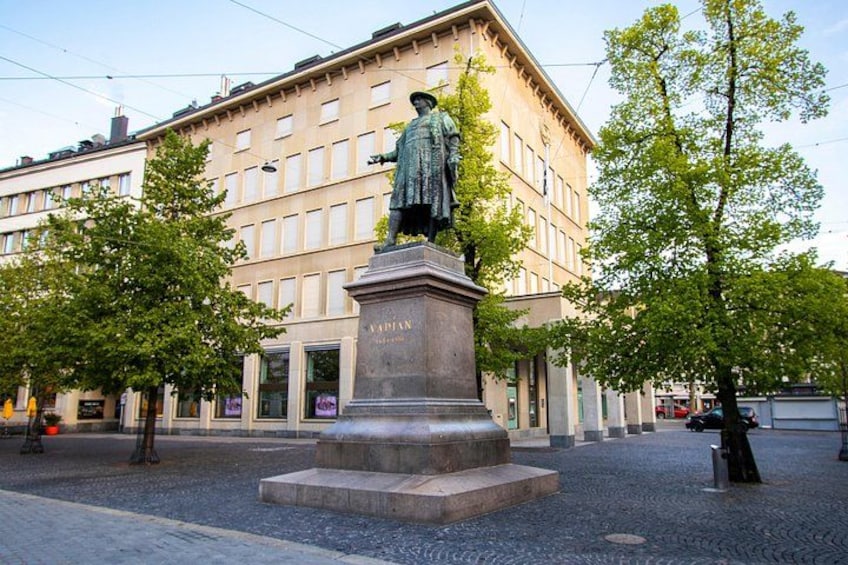 A statue on a pedestal in a square with trees and a building in the background. 4