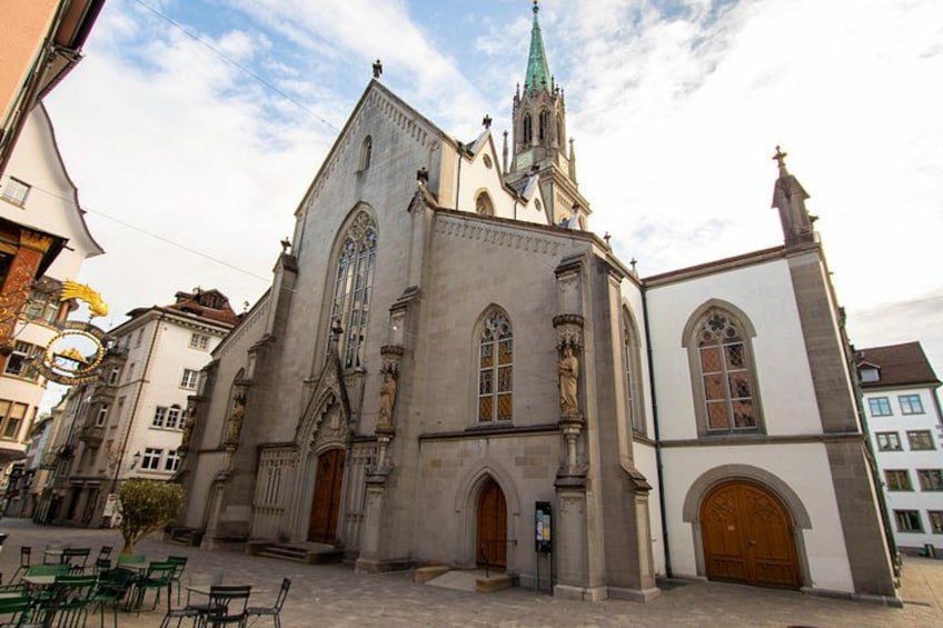 A historic church with a tall spire, arched windows, and a large wooden door. 1
