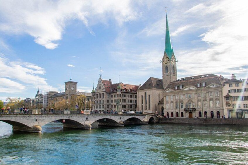 A bridge over a river with historic buildings and a tall church spire. 3