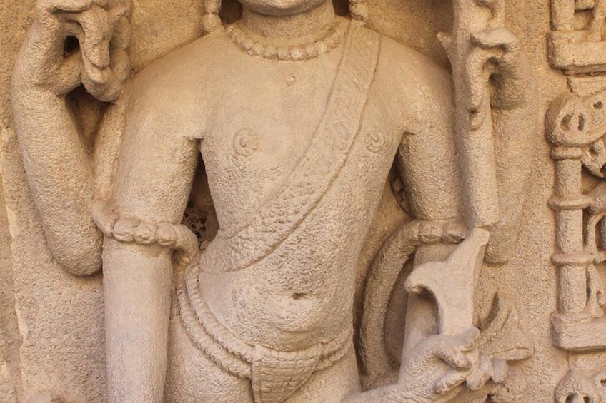 Une sculpture en pierre représentant une divinité à plusieurs bras, ornée de motifs complexes et vêtue d’un habit traditionnel drapé. 5