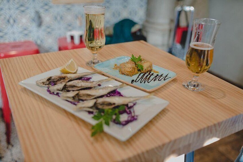 A wooden table with two plates of food and two glasses of beer. 3