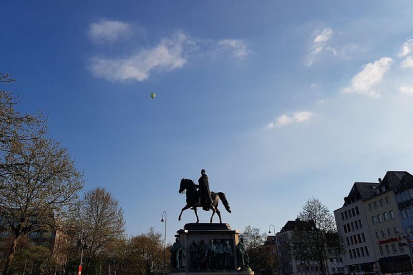A statue of a person on horseback, a clear blue sky, and buildings in the background. 2