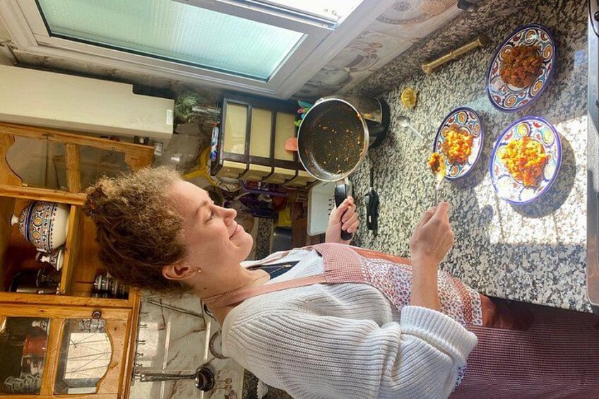 A person cooking in a kitchen with a stove, pots, and plates of food. 3