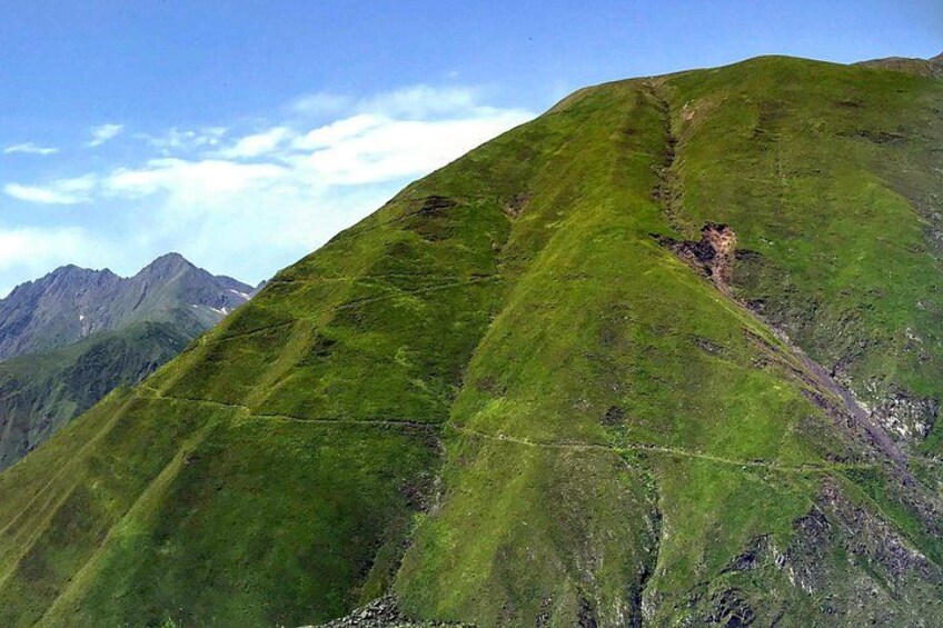 A mountain with a green slope and a visible trail. 5