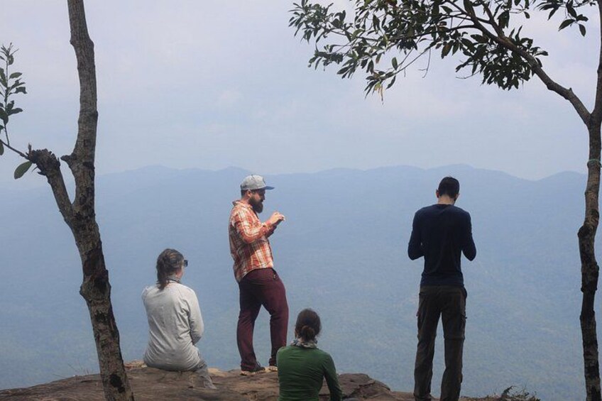 Three people standing on a rocky outcrop overlooking a mountainous landscape. 1