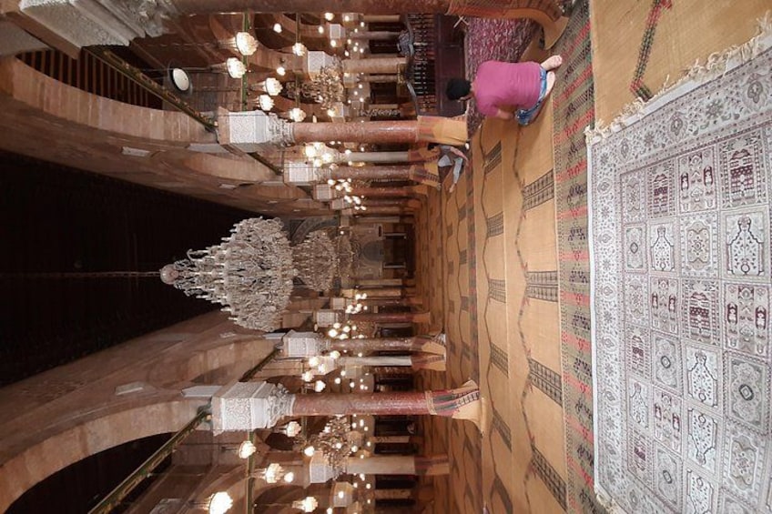 A grand hall with ornate chandeliers, a patterned carpet, and a large chandelier. 5