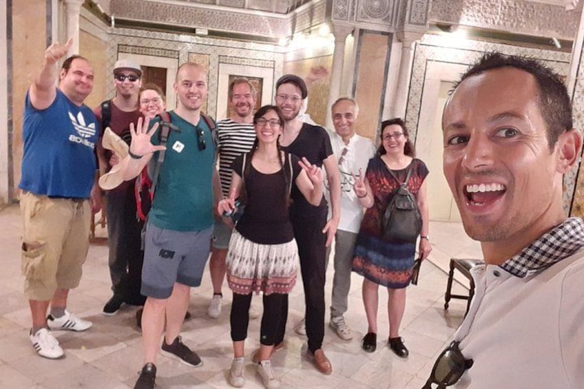 A group of people posing in a historic building with ornate columns and a tiled floor. 2