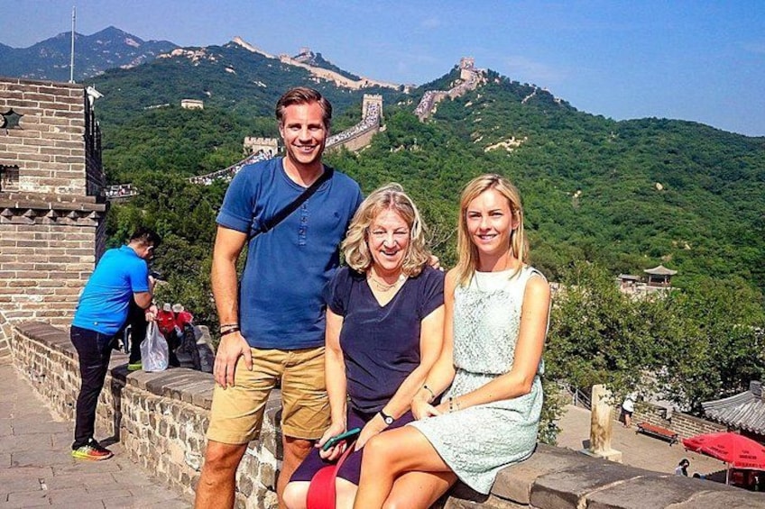 A group of people on a historical site with a large wall and a mountain in the background. 1