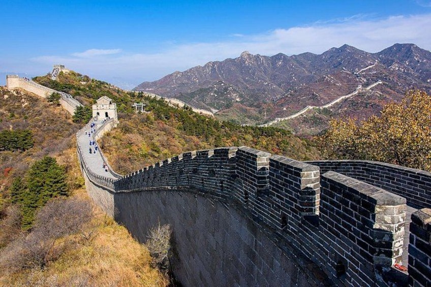 The Great Wall of China, a historic fortification, with a mountainous backdrop and clear sky. 5