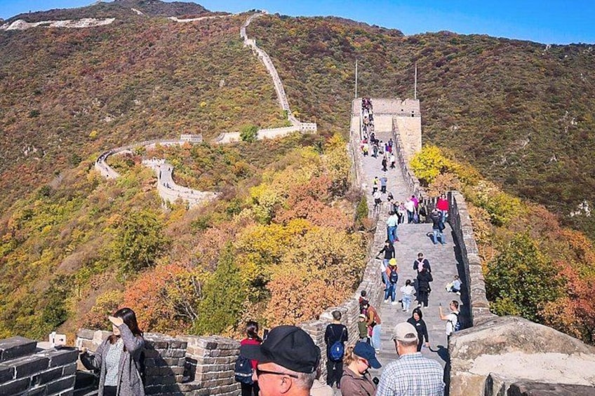 The Great Wall of China winding through a mountainous landscape with visitors walking along the path. 3