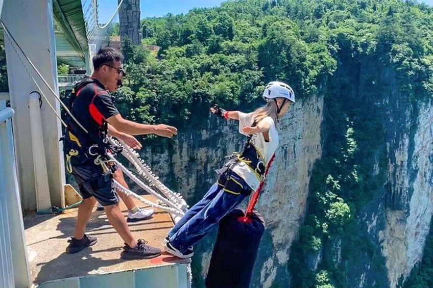 A person bungee jumping with a guide on a platform overlooking a deep gorge. 2