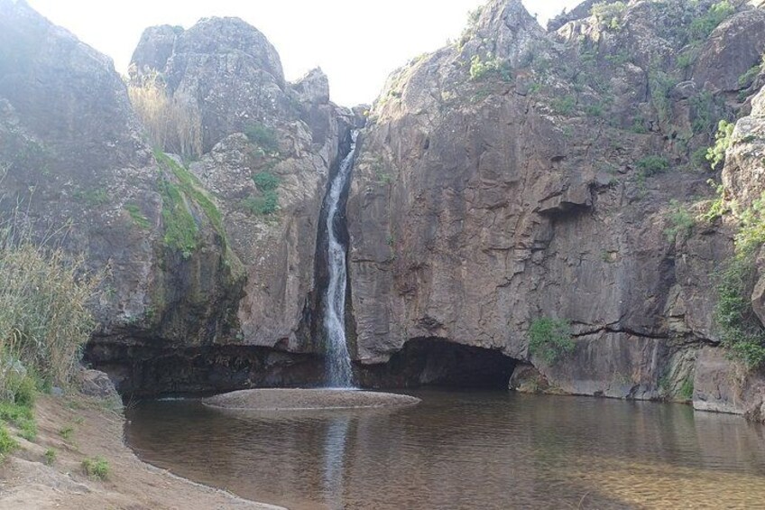 A waterfall cascading into a pool surrounded by rocky cliffs. 4