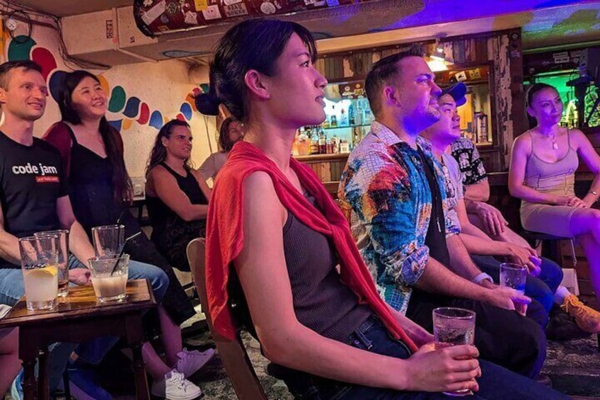 A group of people seated at a bar, some holding drinks. 4