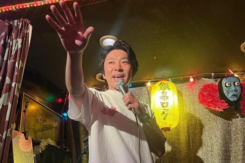 A person holding a microphone, a traditional lantern, and a mask. 2