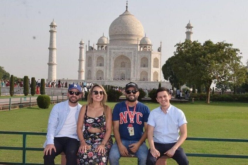 Vier personen zitten op een bankje, met de Taj Mahal op de achtergrond. 4