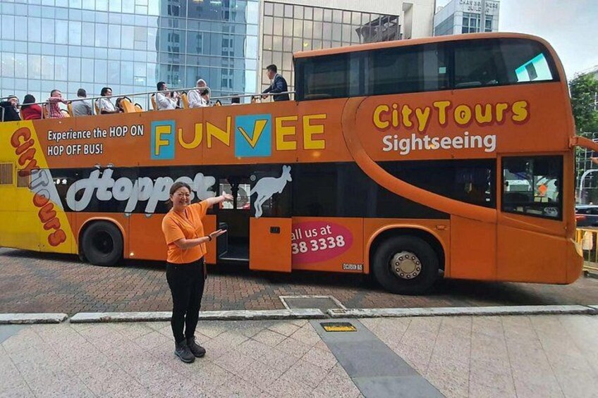 En tvåvåningsbuss med logotyperna för "CityTours Sightseeing" och "FunVee", en person som gestikulerar och en stadsbild i bakgrunden. 1