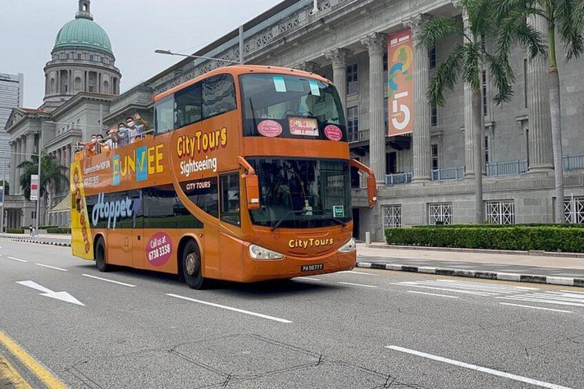 En tvåvåningsbuss med reklam för "City Tours Sightseeing" och "FunVee", som kör på en stadsgata med en stor byggnad i bakgrunden. 5