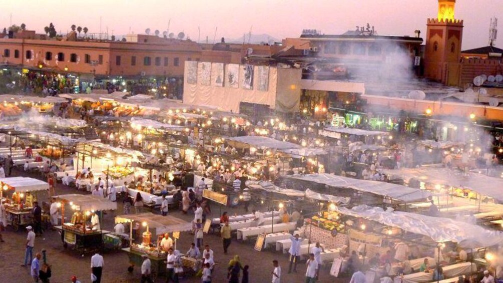 A bustling outdoor market at dusk with numerous stalls and people. 2