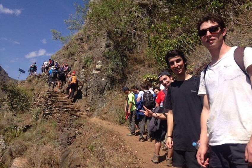 A group of hikers ascending a rocky trail surrounded by vegetation. 2