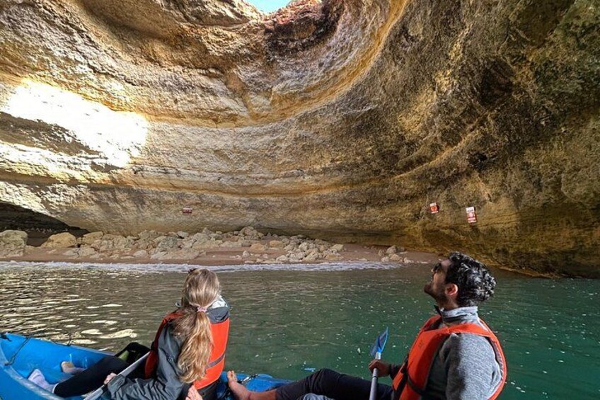 A cave with a river inside, a person in a kayak, and another person in a boat. 4