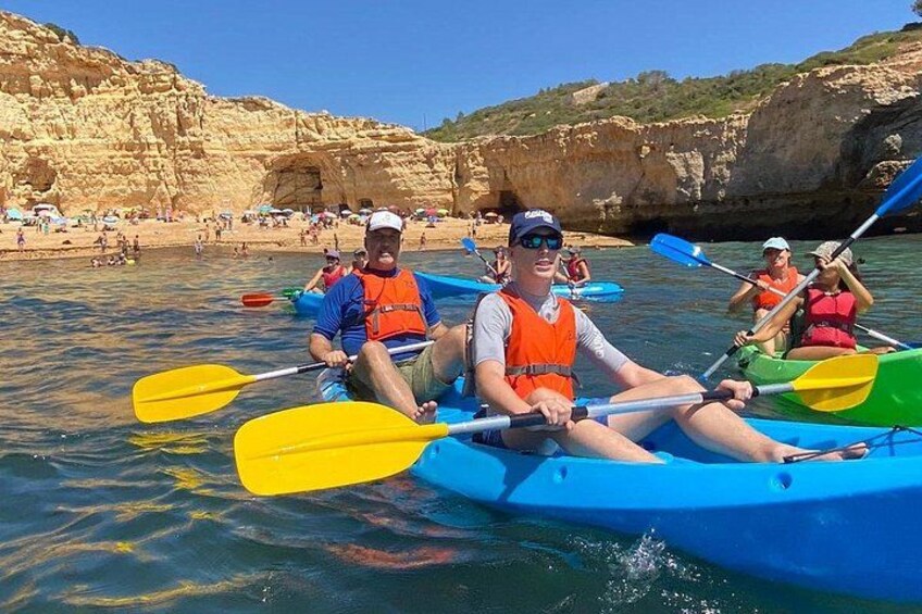 People kayaking on a calm body of water with rocky cliffs in the background. 2
