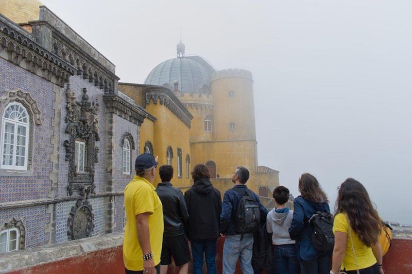 A group of people standing on a red platform, overlooking a historic building with a dome and intricate architecture. 4