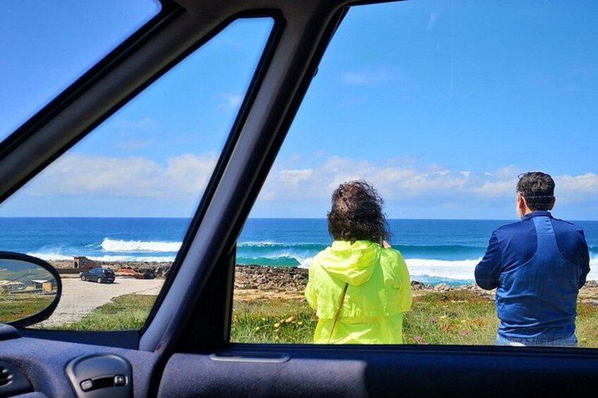 A car's interior with a view of the ocean and a rocky shoreline. 5