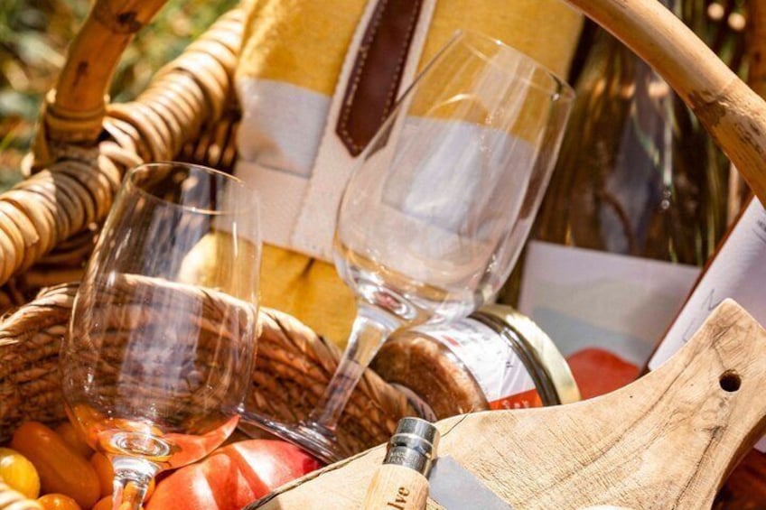 Una cesta de mimbre con copas de vino, un sacacorchos y una botella de vino. 4