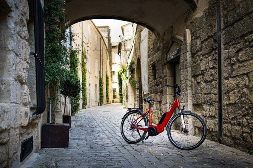A narrow cobblestone street with a red bicycle parked under an archway. 3