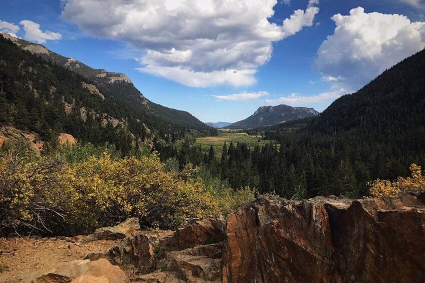 A mountainous landscape with a valley, rocky outcrops, and dense forests. 2